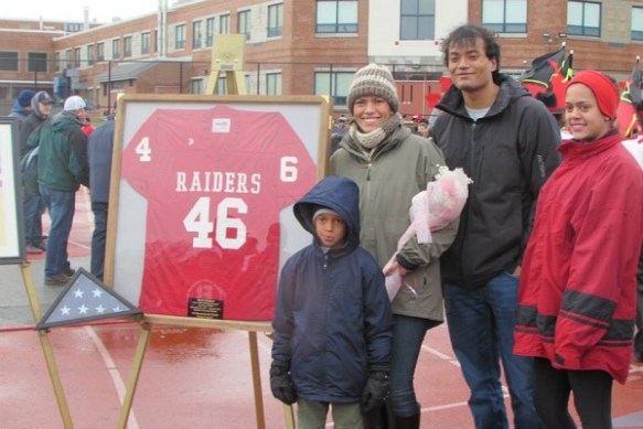 Kevin Houston's wife, Meiling, and their three children stand proudly beside his retired #46 jersey that will be displayed prominently at Barnstable High School. Meiling was presented with a jersey and flowers at the ceremony in honor of her late husband's heroism. 